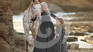 Woman with daughter and mottled horse slow motion full hd