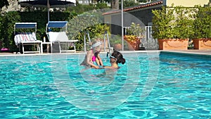 Woman and Daughter Playing in a Pool Outdoors