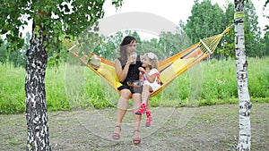 Woman with Daughter Relaxing in Hammock in Summer