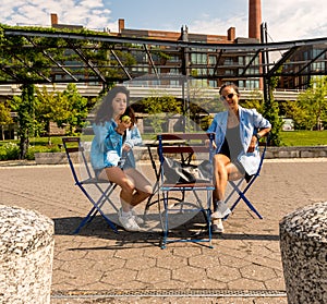 Woman and daughter sitting at table on walkway