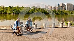 Woman and daughter sitting at table on walkway