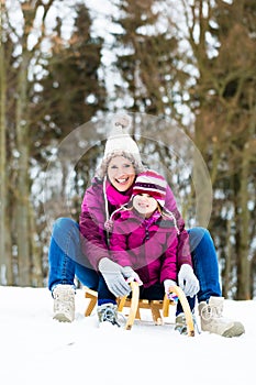 Woman and daughter on sled in winter