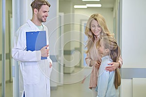 Woman and daughter standing in front of man with folder
