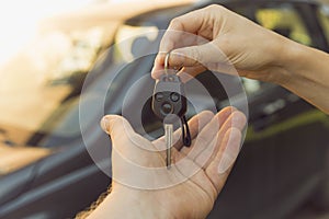 Woman dealer hand giving car keys to man, car on the background