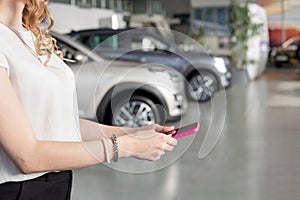 Woman dealer using mobile smart phone at dealer showroom. Modern working process