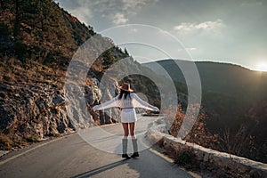 The woman is dear to the mountains. A woman in a white sweater, black boots and a hat walks along a winding alpine path