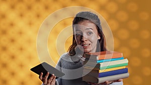 Woman debating between physical books and ebooks on ereader, studio background