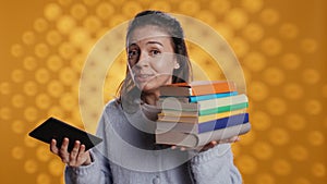 Woman debating between physical books and ebooks on ereader, studio background