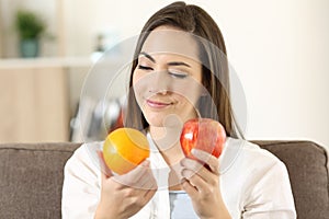 Woman deciding between an orange and apple photo