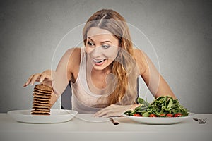 Woman deciding whether to eat healthy food or sweet cookies she craving