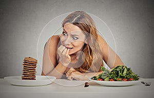 Woman deciding whether to eat healthy food or sweet cookies she craving