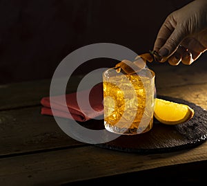 Woman decorat Orange Twist alcoholic cocktail negroni on a old wooden board. Drink with gin, campari martini rosso and orange, an