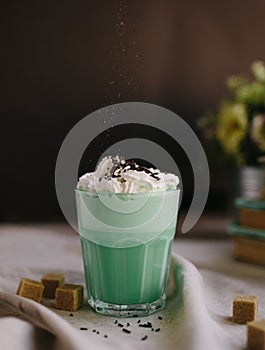 Woman decorate with colored edible sparkles green mint coffee. Milk shake, cocktaill, frappuccino.