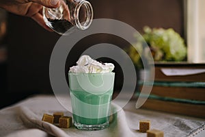 Woman decorate with colored edible sparkles green mint coffee. Milk shake, cocktaill, frappuccino.