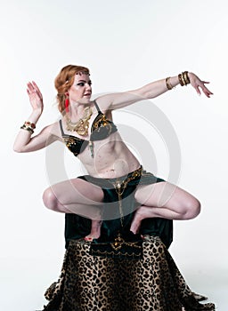 Woman in decorated traditional green belly costume with top and skirt dancing on pedestal with leopard print