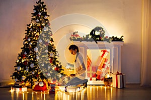 Woman decorates the Christmas tree Garland lights new year holiday gifts white home decor