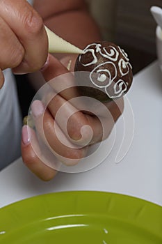 A woman decorates with the help of white chocolate popcake glazed with dark chocolate
