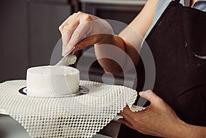 Woman during decorating cake with cream