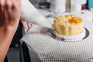 Woman during decorating cake with cream