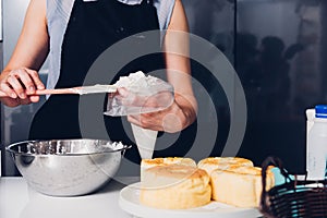 Woman during decorating cake with cream