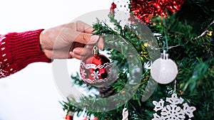 Woman decorating christmas tree with red balls in room house. Xmas ornaments