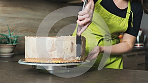 woman decorating a delicious layered sponge cake with chocolate icing cream