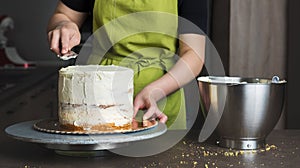 Woman decorating a delicious layered sponge cake with icing cream