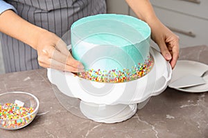 Woman decorating fresh delicious birthday cake in kitchen