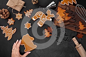 Woman decorating gingerbread Christmas cookies with icing sugar. Christmas preparations concept. Top view with copy