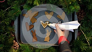 Woman decorating gingerbread cookies with cream, Christmas baking, preparations