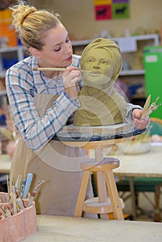 woman decorating head in pottery class