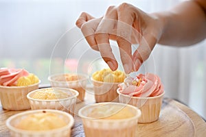 Woman decorating her fresh baked homemade cupcake in the kitchen