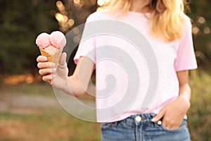 Woman with delicious ice cream in waffle cone outdoors, closeup