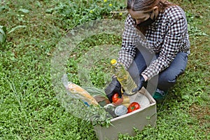 Woman delivering donations box with food during Covid 19 outbreak.Feme volunteer collects food in a box standing on the grass photo