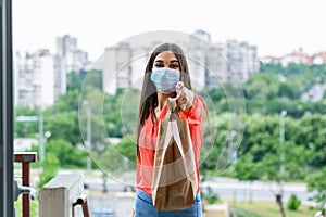 Woman delivering food in paper bag during Covid 19 Coronavirus outbreak.Feme volunteer holding groceries in the house porch photo