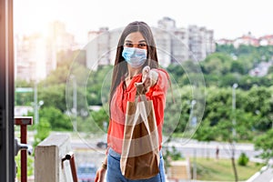 Woman delivering food in paper bag during Covid 19 Coronavirus outbreak.Feme volunteer holding groceries in the house porch photo