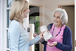 Woman Delivering Newspaper To Elderly Neighbour photo