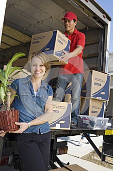 Woman With Delivery Man Unloading Moving Boxes From Truck