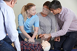 Woman Demonstrating CPR On Training Dummy In First Aid Class