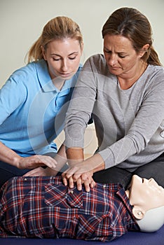 Woman Demonstrating CPR On Training Dummy In First Aid Class