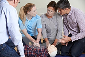 Woman Demonstrating CPR On Training Dummy In First Aid Class