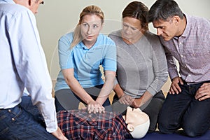 Woman Demonstrating CPR On Training Dummy In First Aid Class