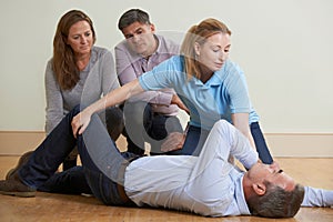 Woman Demonstrating Recovery Position In First Aid Training Class