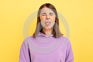 Woman demonstrating tongue, behaving naughty unruly, childish mood, closed eyes.