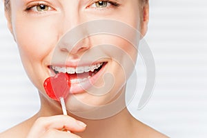 Woman with dental braces biting red lollipop photo