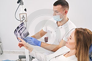 Woman and dentist analyzing dental x-ray scan in clinic