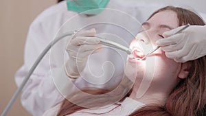 A woman dentist in Asia examines a lady`s oral cavity. A woman has a dental check-up in a clinic