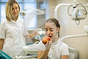 Woman dentist gives apple for smiling teenage girl