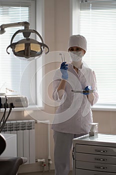 A woman dentist in her medical office, tools in hand.