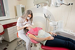 Woman dentist in her office treating female patient